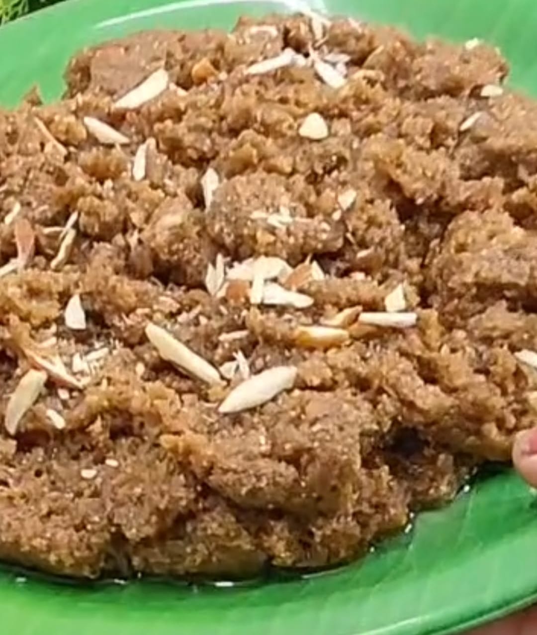 Gond ka halwa topped with slivered almonds on a green plate
